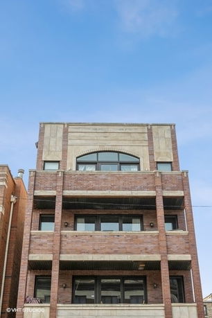 Front view of a multi-story brick building with balconies.