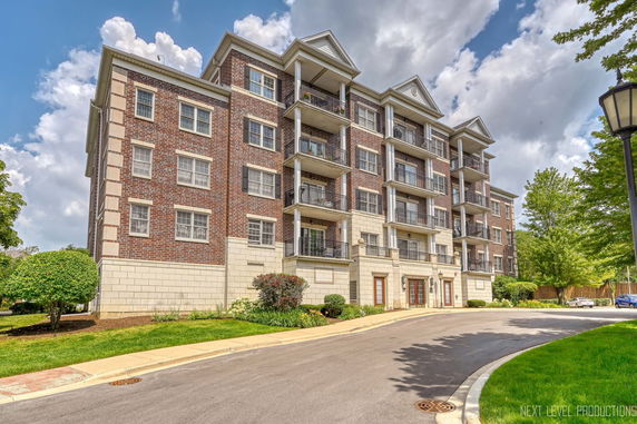 Front view of a multi-story residential building with balconies and brick facade.