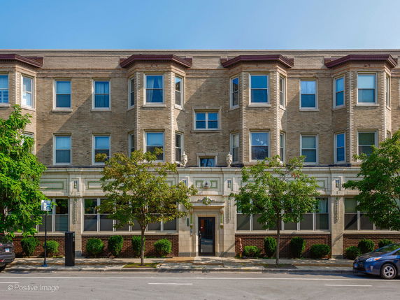 Front view of a three-story apartment building with brick exterior and multiple windows.