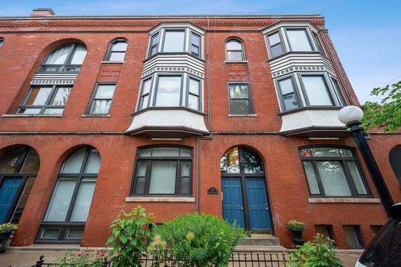 Front view of a multi-story brick building with arched windows and blue doors.