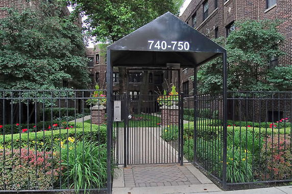 Front view of a brick apartment building entrance with a gated walkway.