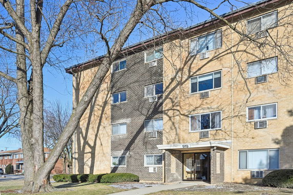 Front view of a multi-story brick apartment building with multiple windows.