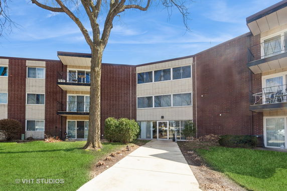 Front view of a multi-story brick apartment building with balconies.