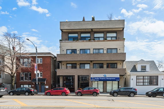 Front view of a multi-story building with balconies and a property management office on the ground floor.