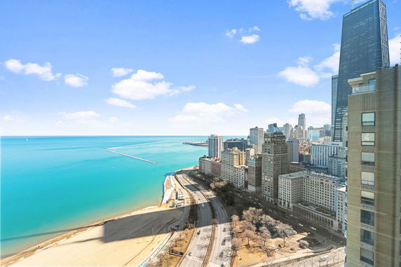 Panoramic view of a city skyline with tall buildings and a large body of water.