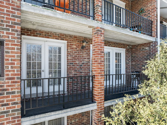 Front view of a multi-story building with brick exterior and balconies.