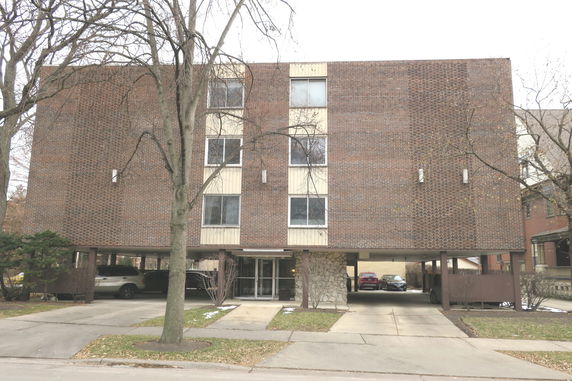 Front view of a three-story building with parking space on the ground level.