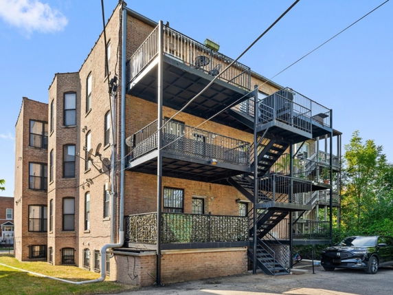 Side view of a multi-story brick building with external metal staircases and balconies.