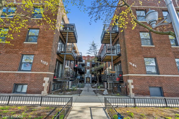 Front view of a multi-story brick apartment building with balconies.