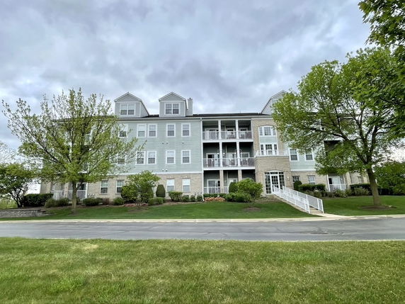 Front view of a multi-story residential building with a central porch and a ramp leading to the entrance.