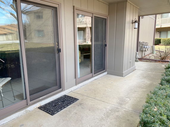 Front view of a building with sliding glass doors and an exterior light fixture.