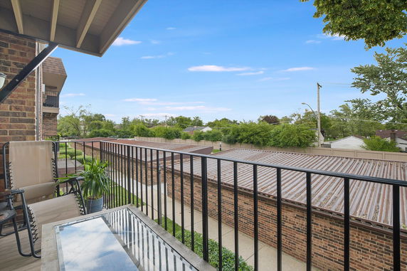 View from a balcony overlooking rooftops and trees.