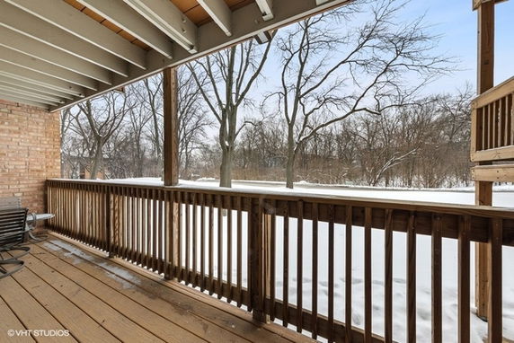 View from a wooden deck overlooking a snowy landscape with trees.
