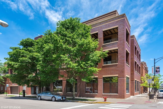 Front view of a multi-story brick building with large windows.