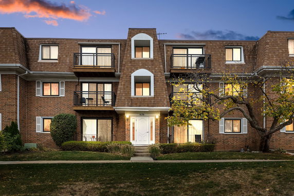 Front view of a three-story brick building with multiple balconies.
