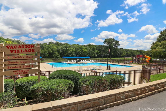 Outdoor swimming pool area with lounge chairs and a playground nearby.