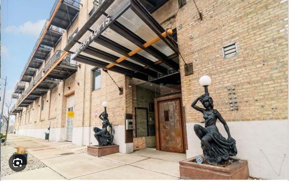 Front view of a brick building with statues and a glass awning entrance.