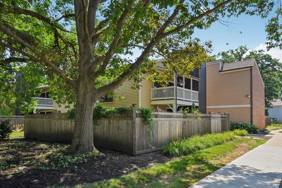 Front view of a house with a wooden fence and upper balcony.