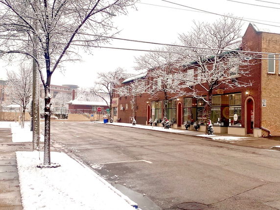 Street view of a two-story brick building with decorated storefronts.
