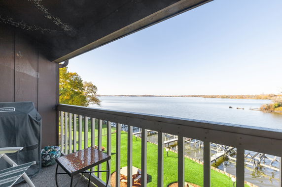 Balcony view overlooking a lake with docks and grassy area.