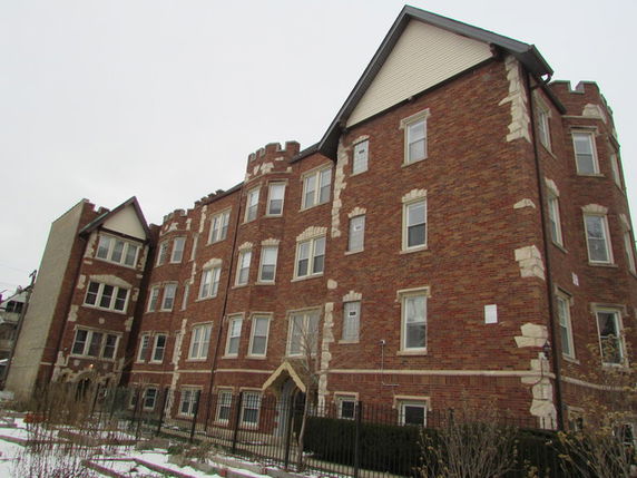 Front view of a multi-story brick apartment building with multiple windows and a decorative entrance.