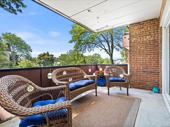 Outdoor seating area with wicker furniture and a view of trees in the background.