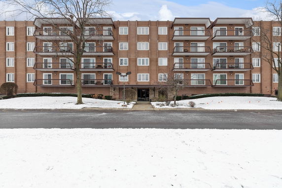 Front view of a multi-story brick apartment building with balconies.