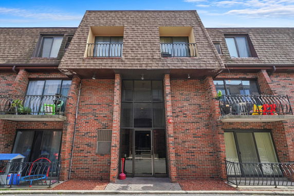 Front view of a three-story brick building with balconies and a central entrance.