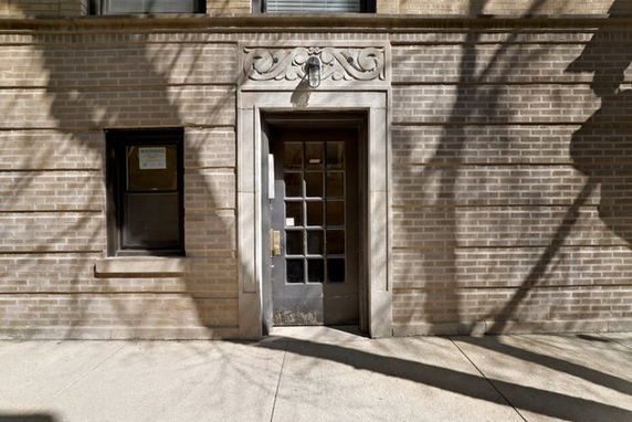 Front view of a building entrance with brick facade and ornate door frame.