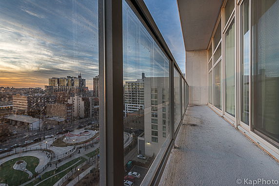Panoramic view from a balcony overlooking a cityscape at sunset.
