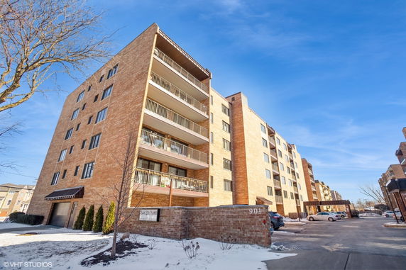 Front view of a multi-story brick apartment building with balconies.
