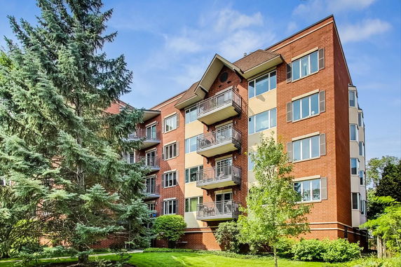 Front view of a multi-story brick apartment building with balconies.