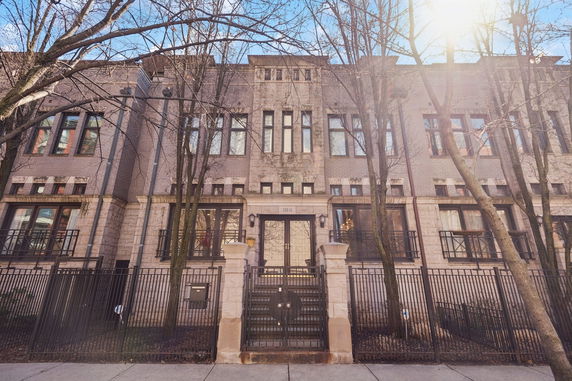 Front view of a multi-story building with a gated entrance and large windows.