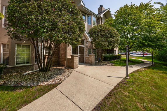 Front view of a multi-story residential building with a landscaped entrance.