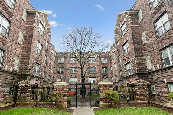 Front view of a brick apartment complex with gated entrance.