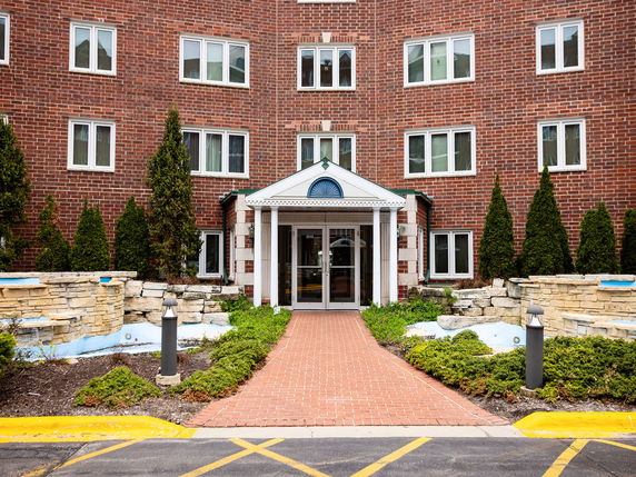 Front view of a brick apartment building with multiple windows and a covered entryway.
