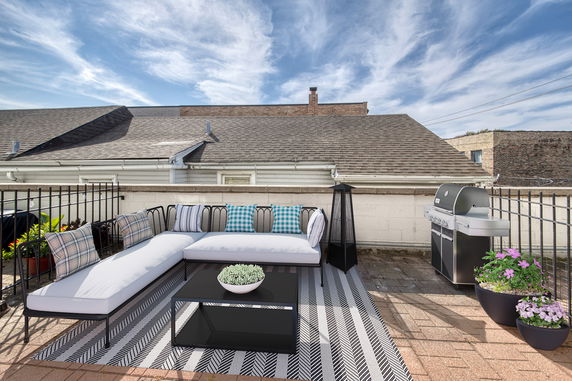 Rooftop with seating area, grill, and decorative plants.