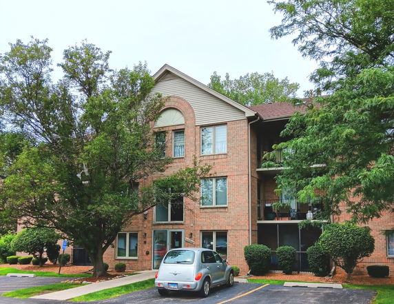 Front view of a multi-story brick residential building with balconies.