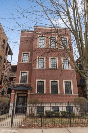 Front view of a three-story brick building with multiple windows.