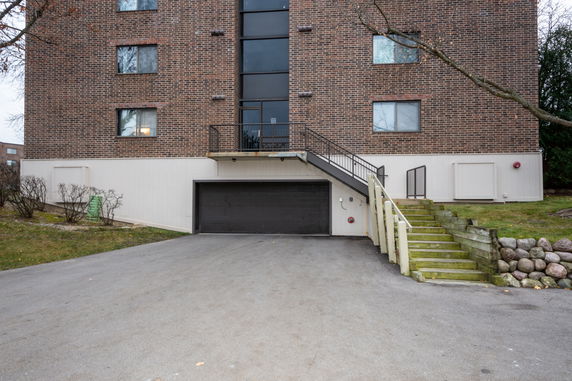 Front view of a multi-story brick building with a garage entrance and stairway.