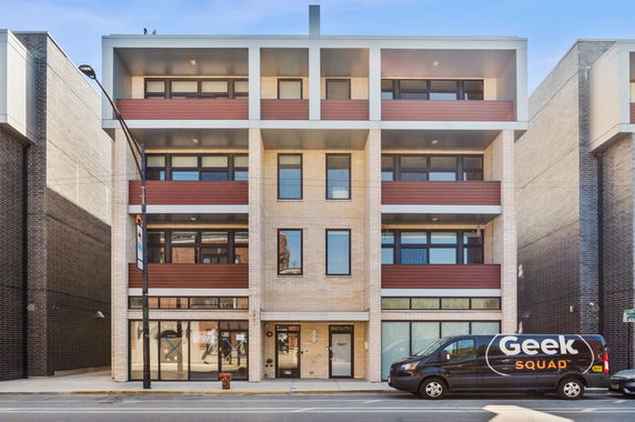 Front view of a multi-story building with large windows and balconies.
