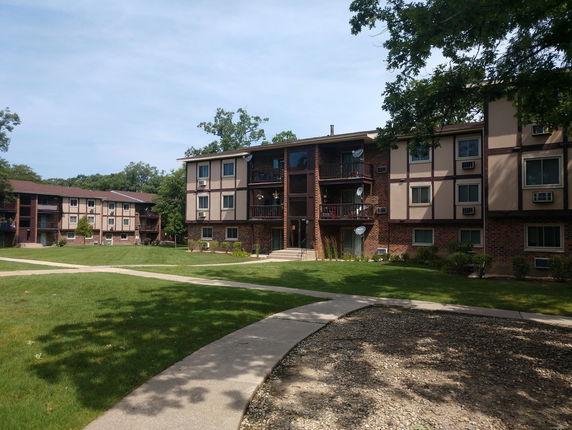 Front view of a multi-story apartment building with brick and siding exterior.
