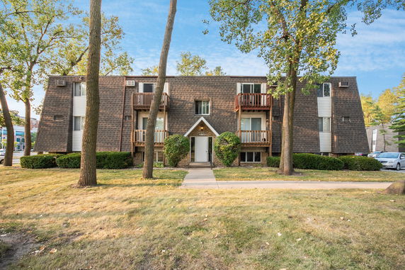 Front view of a two-story apartment building with a triangular entryway and balconies.
