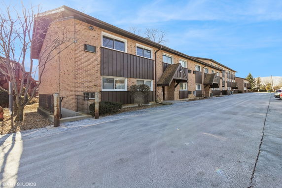 Front view of a multi-story brick building with brown accents and multiple entryways.