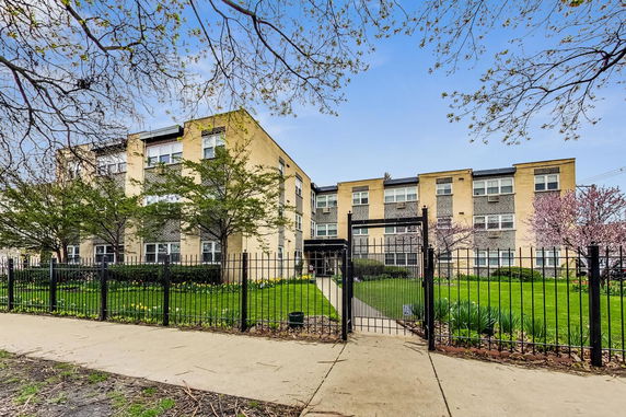 Front view of a three-story apartment building with a gated entrance.