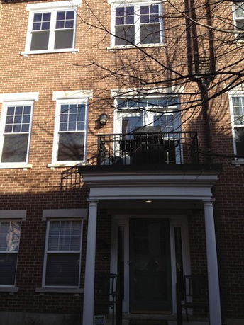 Front view of a multi-story brick house with a small balcony.