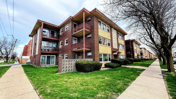 Front view of a multi-story brick apartment building with balconies.