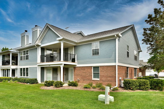 Front view of a two-story house with gray siding and brick base.
