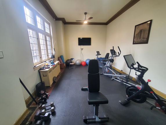 Indoor gym area with exercise equipment and weights.