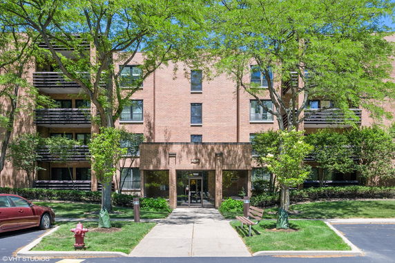 Front view of a multi-story brick building with balconies and a central entrance.